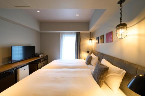 a hotel room with two beds and a television at Hotel Resol Akihabara in Tokyo