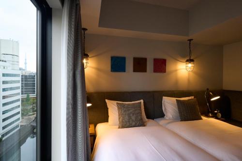 a bedroom with two beds and a large window at Hotel Resol Akihabara in Tokyo