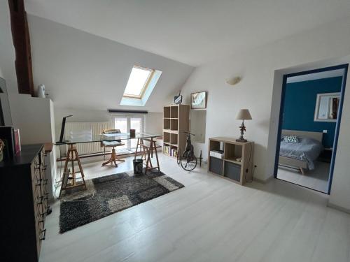Cette grande chambre blanche comprend un lit et une table. dans l'établissement Charmante Maison proche Chartres, à Lèves