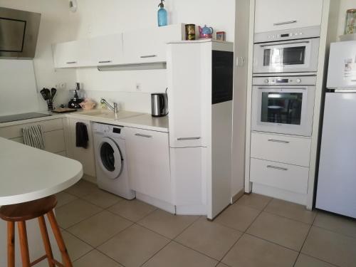 - une cuisine avec des appareils électroménagers blancs et une table dans l'établissement L'Arago, à Nîmes