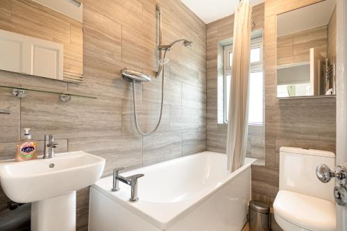 uma casa de banho com uma banheira, um lavatório e um WC. em Renovated 2-Storey 2BR wGarden near Angel St em Londres