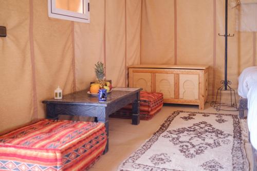 a room with a table and two ottomans in a room at Camel Luxury Camp in Merzouga