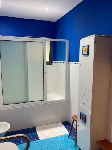 baño con paredes azules, ventana y lavabo en Quinta de Santana - Queimadas, en Furnas