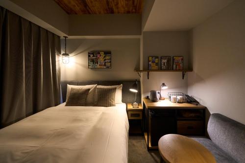 a small bedroom with a bed and a couch at Hotel Resol Akihabara in Tokyo
