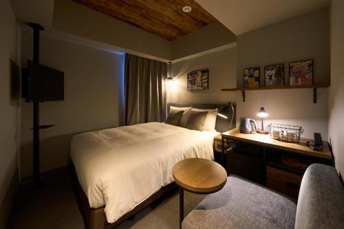 a bedroom with a bed and a desk and a chair at Hotel Resol Akihabara in Tokyo