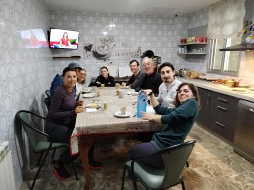a group of people sitting around a table in a kitchen at Pensión Casa do Gallo Sarria in Sarria