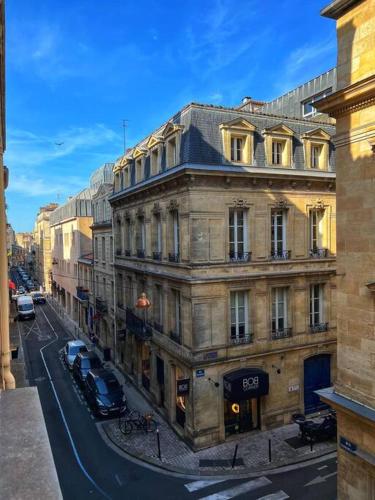 un vieux bâtiment avec des voitures garées dans une rue de la ville dans l'établissement La Perle Citadine, à Bordeaux