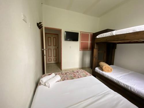 a bedroom with two bunk beds and a television at Mahalo Hostel in Salento