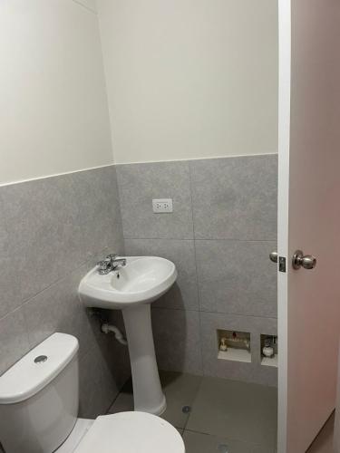ein Badezimmer mit einem weißen WC und einem Waschbecken in der Unterkunft La Huaca Los Olivos - Departamento in Lima