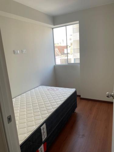 ein Schlafzimmer mit einem Bett in einem Zimmer mit einem Fenster in der Unterkunft La Huaca Los Olivos - Departamento in Lima