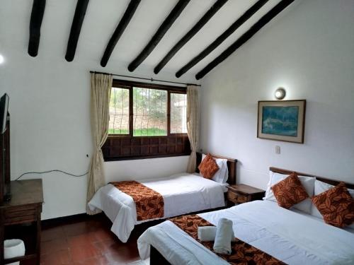 a bedroom with two beds and a window at Hotel MAXIRUMA - Villa TAMAUKA in Iza