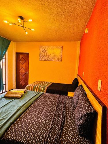 - une chambre avec un lit dans une pièce aux murs orange dans l'établissement Hotel Diamantes, à Orizaba