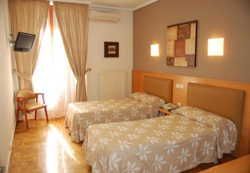 a hotel room with two beds and a chair at Hostal Arotza in Tafalla