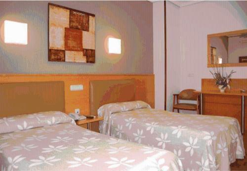 タファリャにあるHostal Arotzaのベッド2台と鏡が備わるホテルルームです。