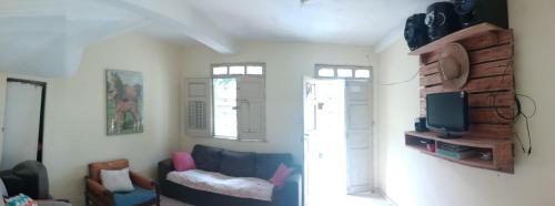 uma sala de estar com um sofá e uma televisão em Casa hostel quarto dormitório estudantil em Ilhéus