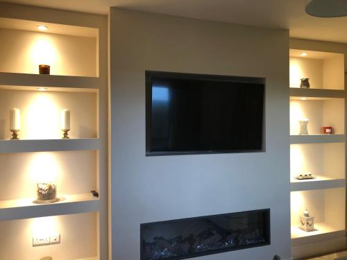 a living room with a flat screen tv and a fireplace at Bungalow in the countryside in Roscommon