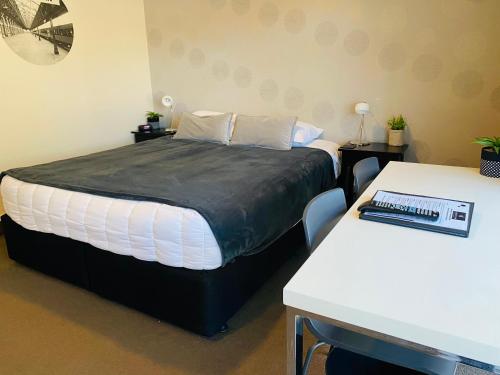 a bedroom with a large bed and two tables at Commodore Motel in Dunedin