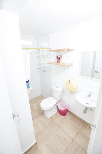 a white bathroom with a toilet and a sink at Hostal Palo Alto in San Andrés