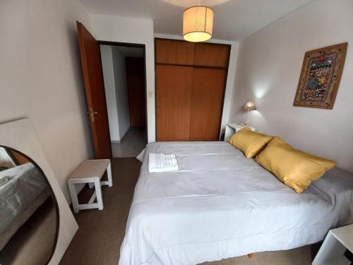 a bedroom with a large bed with a yellow pillow at DEPARTAMENTO CÉNTRICO, a METROS de la UNIVERSIDAD, 3 PERSONAS, GARAJE AUTO CHICO in La Plata