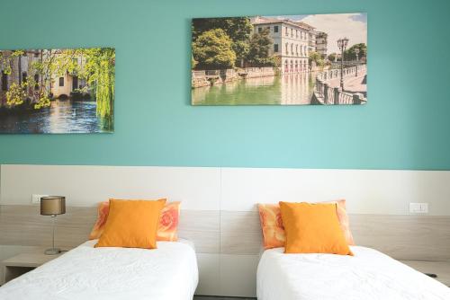 two beds in a room with paintings on the wall at Residence Diamante in Villorba