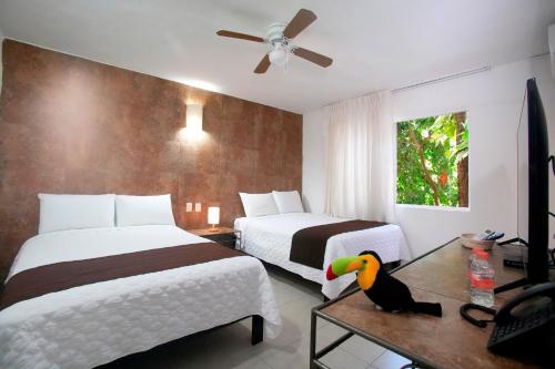 a hotel room with two beds and a parrot on a table at Tukan Hotel Playa del Carmen in Playa del Carmen