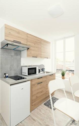 une cuisine avec des appareils électroménagers blancs et des armoires en bois dans l'établissement La résidence Jeanne d'Arc 4, Troyes-France, à Troyes