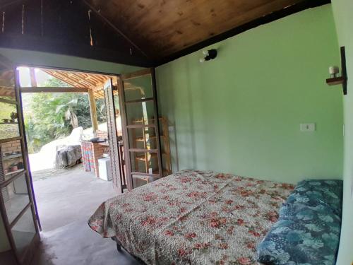 1 dormitorio con 1 cama y puerta corredera de cristal en Chalé Floresta Toca da Serra, en Iporanga