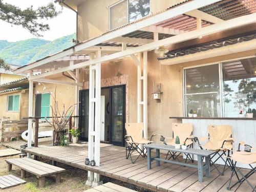 a wooden deck with chairs and a table on a house at Kanzaki Beach House in Kanzaki