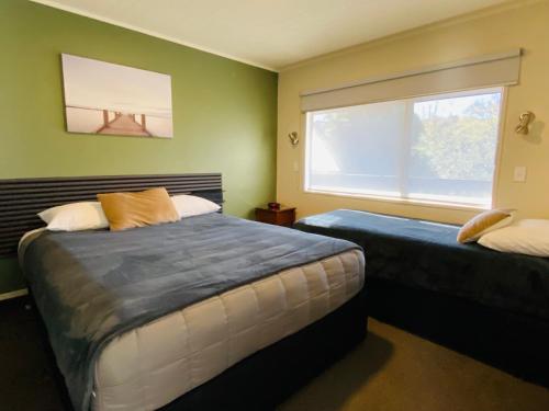 a bedroom with two beds and a large window at Commodore Motel in Dunedin