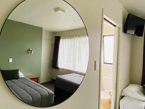 a mirror in a room with a bed and a couch at Commodore Motel in Dunedin