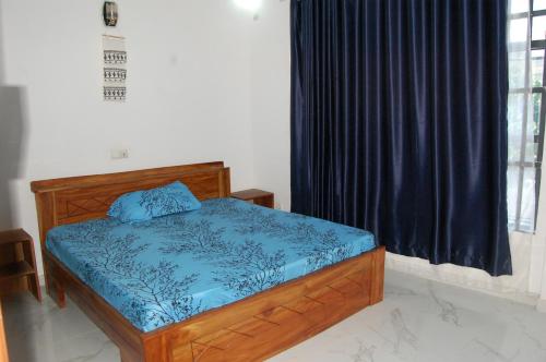 um quarto com uma cama com um edredão azul e uma janela em Les Résidences Oluwa Sheyi em Cotonou