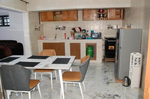 uma cozinha com uma mesa e cadeiras e um frigorífico em Les Résidences Oluwa Sheyi em Cotonou
