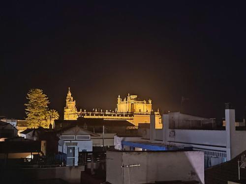 a city at night with a large building in the background at L' Alcoba Rooftop in Sanlúcar de Barrameda