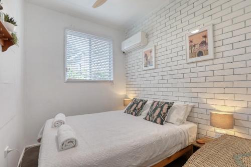 Un dormitorio con una pared de ladrillo blanco y una cama en Sea Salt, en Point Lookout
