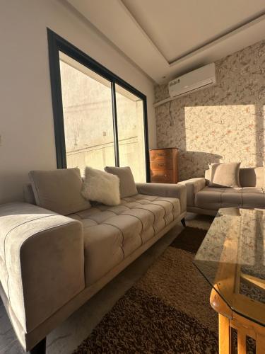 a living room with a couch and a large window at Coquette villa avec piscine in Tunis