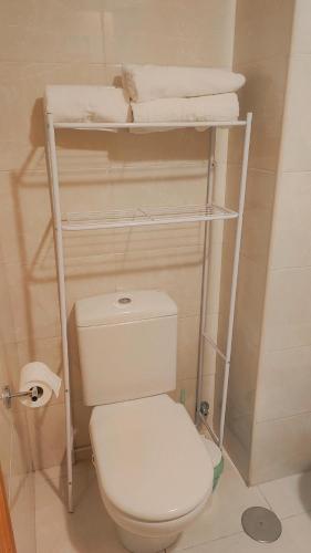 a bathroom with a toilet and a shelf with towels at Habitación Renfe in Pamplona