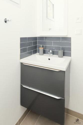 La salle de bains est pourvue d'un lavabo blanc et de carrelage bleu. dans l'établissement La résidence Jeanne d'Arc 1 , Troyes - France, à Troyes