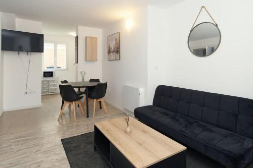 un salon avec un canapé noir et une table dans l'établissement La résidence Jeanne d'Arc 1 , Troyes - France, à Troyes