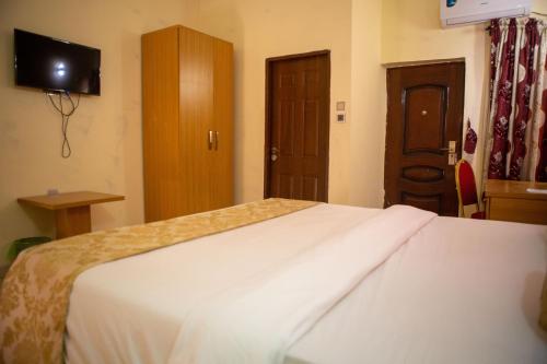 a hotel room with a bed and a tv on the wall at ROSES REGENCY HOTEL AND SUITES in Abuja