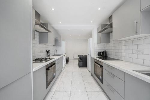 une cuisine blanche avec comptoirs et appareils blancs dans l'établissement A charming 6-bed house with superb transport links, à Londres