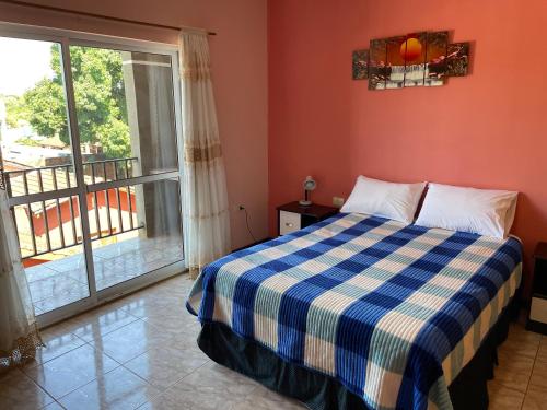 a bedroom with a bed with a blue and white checkered blanket at El Tata in Puerto Iguazú