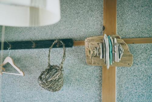 a wooden cross with a basket on a wall at Kanzaki Beach House in Kanzaki