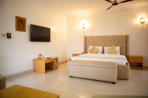 ROSES REGENCY HOTEL AND SUITES في أبوجا: غرفة نوم بسرير كبير وتلفزيون