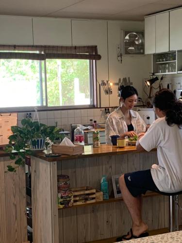Twee vrouwen bereiden eten in een keuken. bij Kanzaki Beach House 