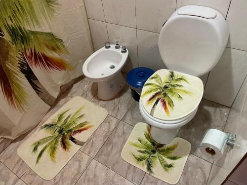 a bathroom with a toilet and a sink with palm trees on mats at El Tata in Puerto Iguazú