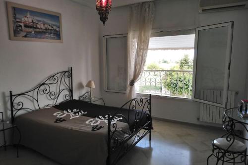een slaapkamer met een zwart bed en een raam bij Maison pied dans l'eau à résidence Jinène Hammamet in Hammamet