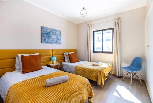 een slaapkamer met 2 bedden en een blauwe stoel bij Vista Mar e Terra in Albufeira