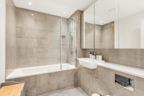 ein Bad mit einer Dusche und einem Waschbecken in der Unterkunft Khayat Homes - The Emerald - Two Bed Luxury Apt in North Woolwich