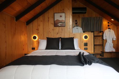 - une chambre avec un grand lit et des murs en bois dans l'établissement Alto's Gardens, à Fortuna