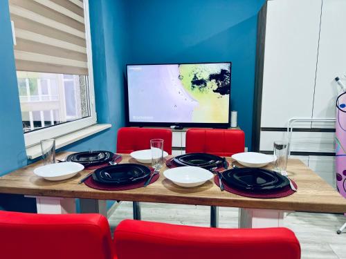 une table à manger avec des chaises rouges et une télévision dans l'établissement NJ Deluxe rooms, à Varna